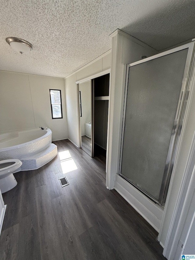 bathroom with hardwood / wood-style flooring, plus walk in shower, a textured ceiling, and toilet