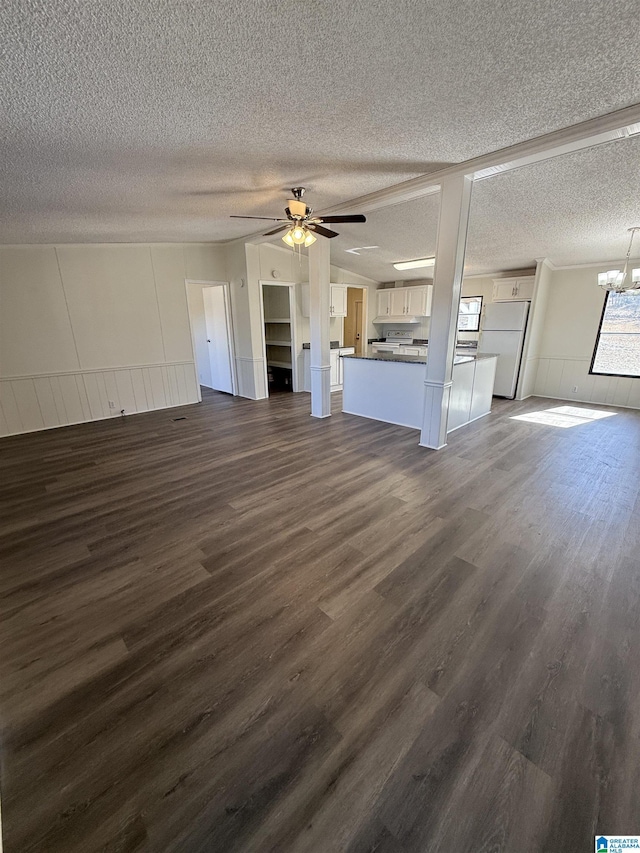 unfurnished living room featuring dark hardwood / wood-style flooring, ceiling fan with notable chandelier, and a textured ceiling