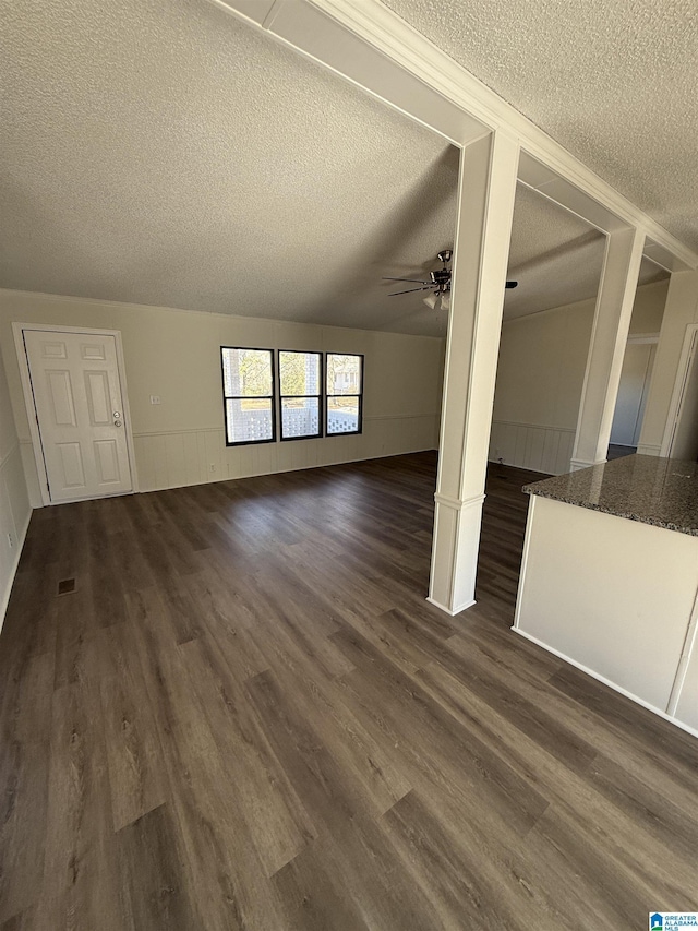 unfurnished living room with dark hardwood / wood-style flooring, ceiling fan, and a textured ceiling