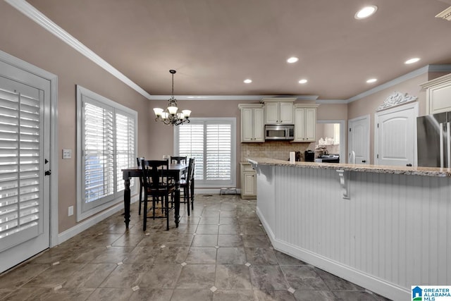 kitchen featuring pendant lighting, stainless steel appliances, light stone counters, and a breakfast bar area