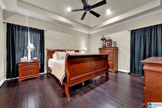 bedroom with dark wood-type flooring, ceiling fan, and a raised ceiling