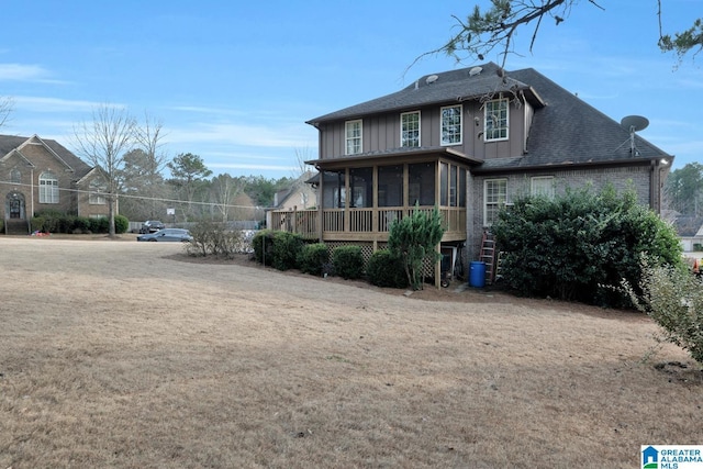 rear view of house with a lawn and a sunroom