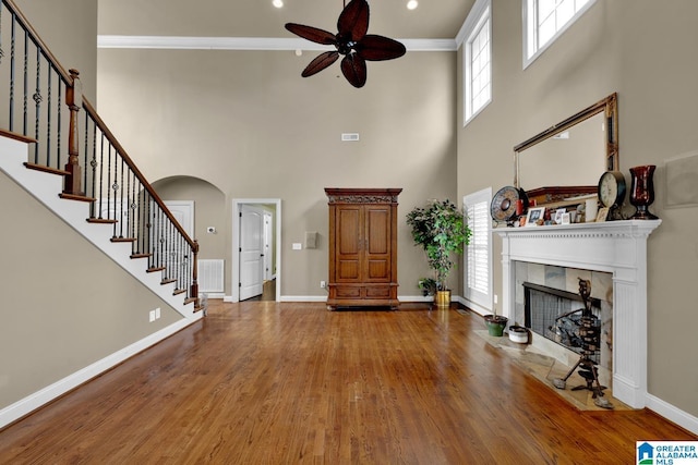 unfurnished living room with hardwood / wood-style flooring, ornamental molding, a fireplace, and a wealth of natural light