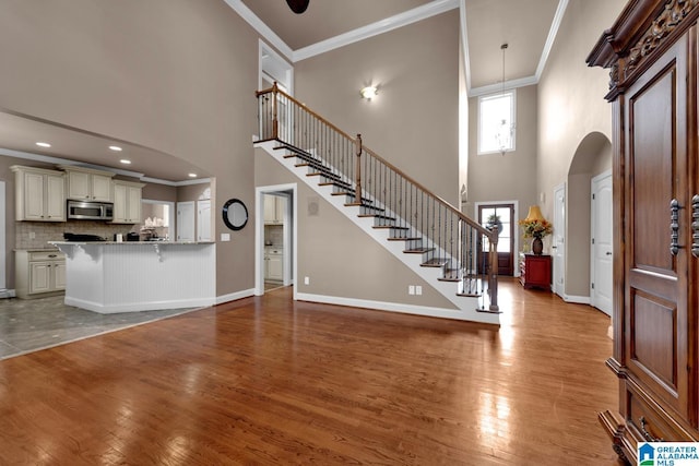 foyer featuring crown molding, light hardwood / wood-style flooring, and a high ceiling