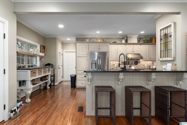 kitchen with white cabinetry, stainless steel fridge, a kitchen breakfast bar, and kitchen peninsula