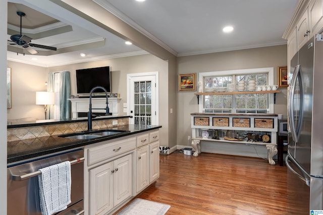 kitchen with ceiling fan, stainless steel appliances, wood-type flooring, ornamental molding, and white cabinets