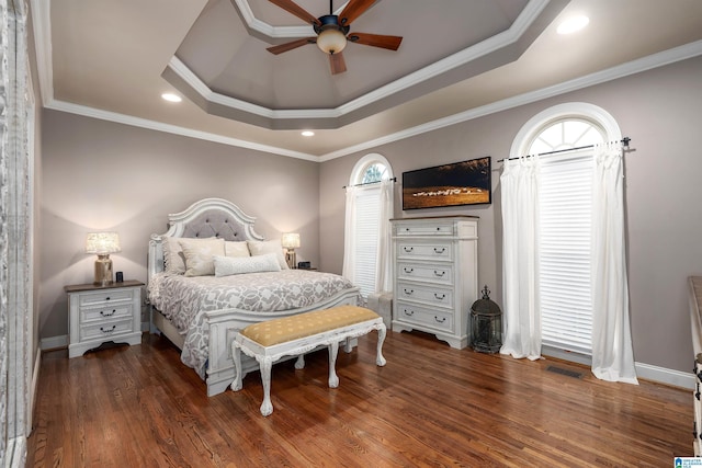 bedroom with a raised ceiling, crown molding, dark wood-type flooring, and ceiling fan