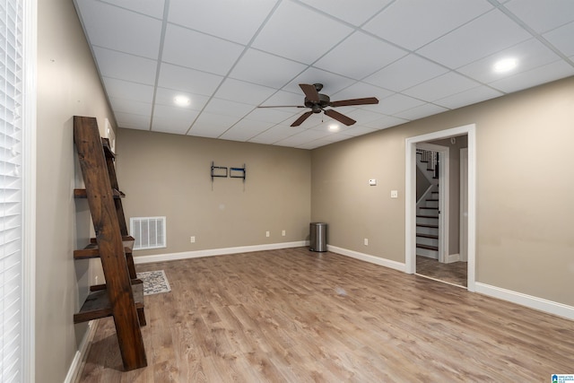 basement with a drop ceiling, light hardwood / wood-style floors, and ceiling fan