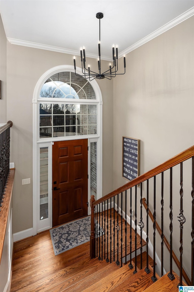 foyer with an inviting chandelier, crown molding, and hardwood / wood-style floors