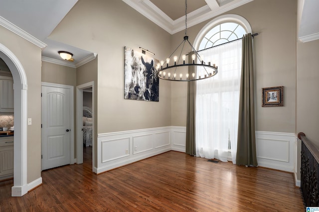 unfurnished dining area with crown molding, an inviting chandelier, and dark wood-type flooring