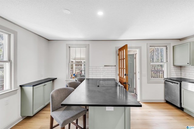 kitchen with dishwasher, plenty of natural light, a kitchen bar, and light hardwood / wood-style floors