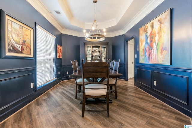 dining area with crown molding, dark hardwood / wood-style flooring, a raised ceiling, and a notable chandelier