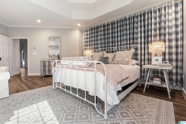 bedroom with crown molding, a raised ceiling, and hardwood / wood-style floors