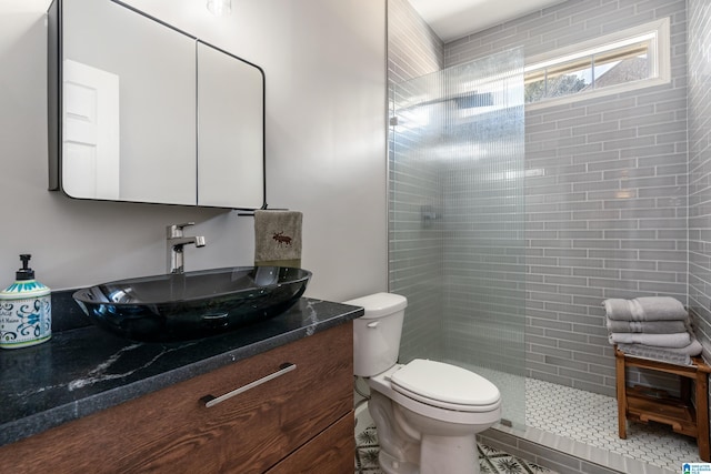 bathroom featuring vanity, a tile shower, and toilet