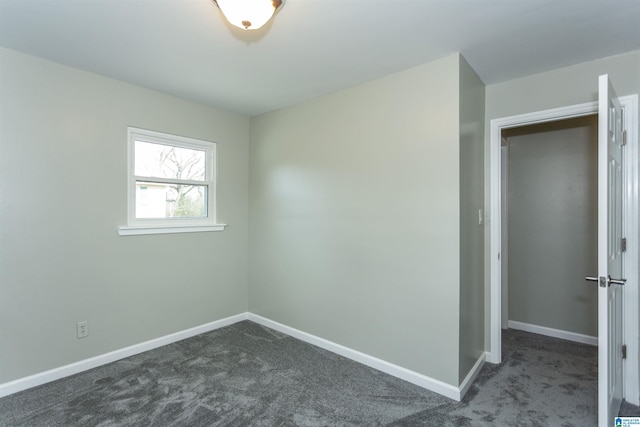 spare room featuring baseboards and dark colored carpet