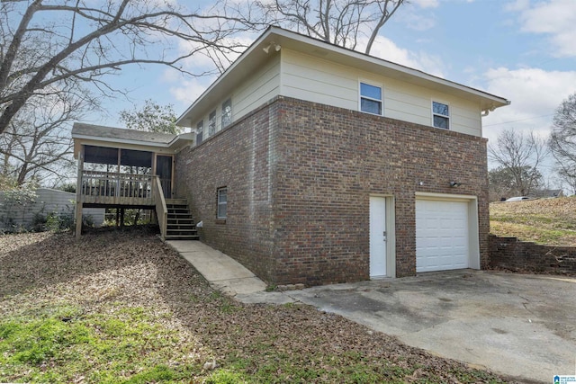 view of home's exterior with brick siding, stairway, concrete driveway, a sunroom, and an attached garage