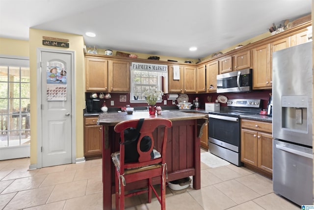 kitchen with stainless steel appliances, a center island, light tile patterned floors, and a breakfast bar