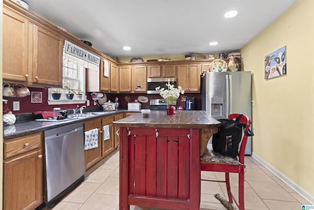 kitchen featuring appliances with stainless steel finishes, sink, a kitchen island, and light tile patterned floors