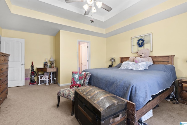 carpeted bedroom featuring a raised ceiling and ceiling fan