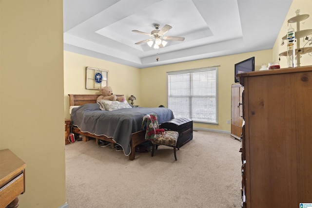 carpeted bedroom with ceiling fan and a raised ceiling