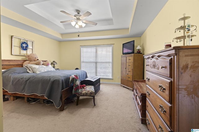 carpeted bedroom with a raised ceiling and ceiling fan