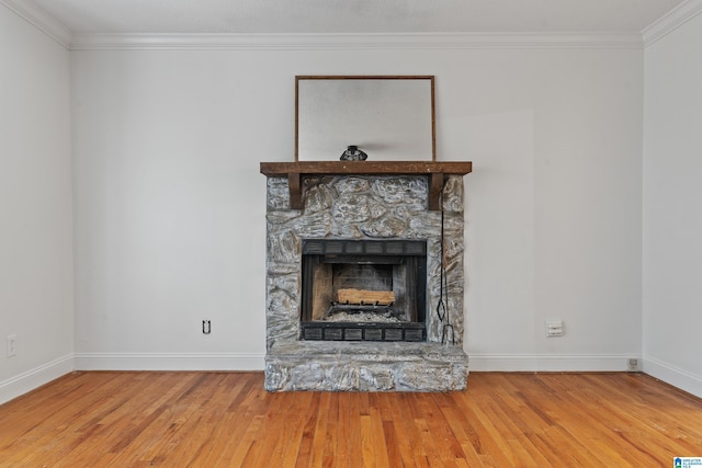 room details with hardwood / wood-style flooring, crown molding, and a stone fireplace