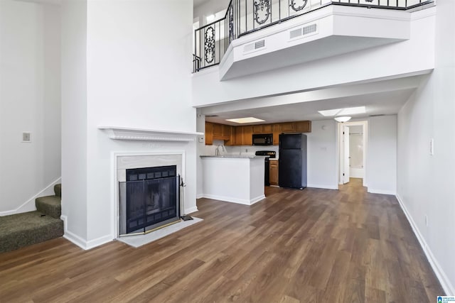 unfurnished living room with a towering ceiling, dark hardwood / wood-style floors, and sink