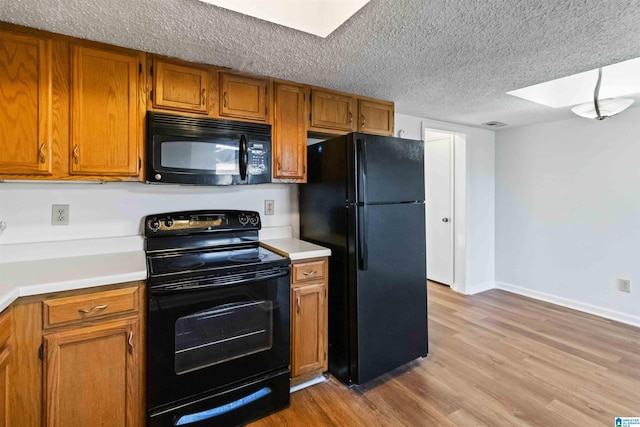 kitchen with a textured ceiling, light wood-type flooring, and black appliances