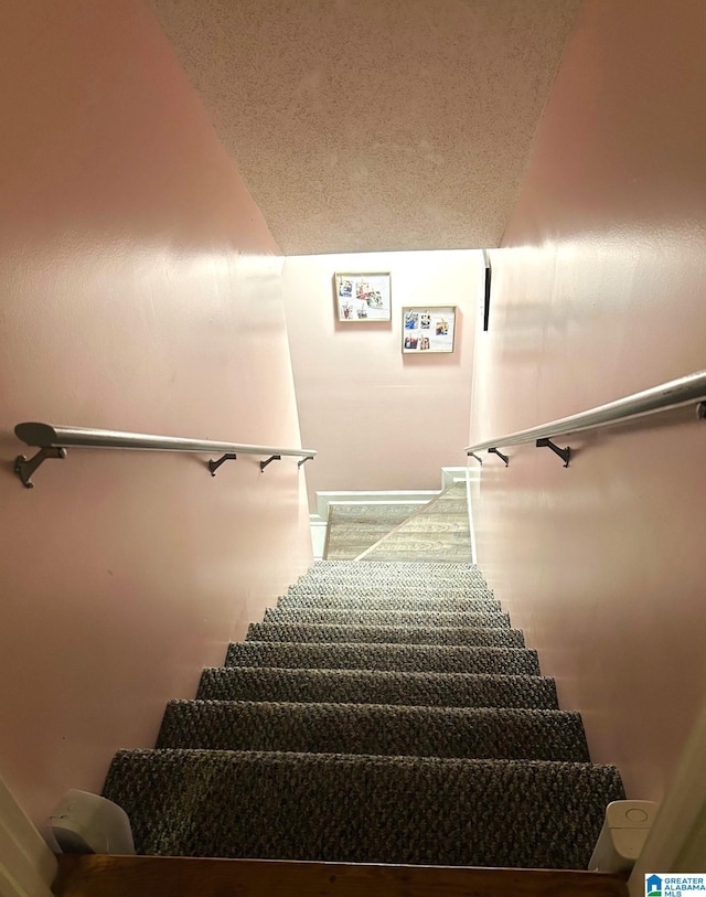 stairs featuring lofted ceiling and a textured ceiling