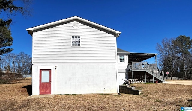 view of side of home featuring a lawn and a deck