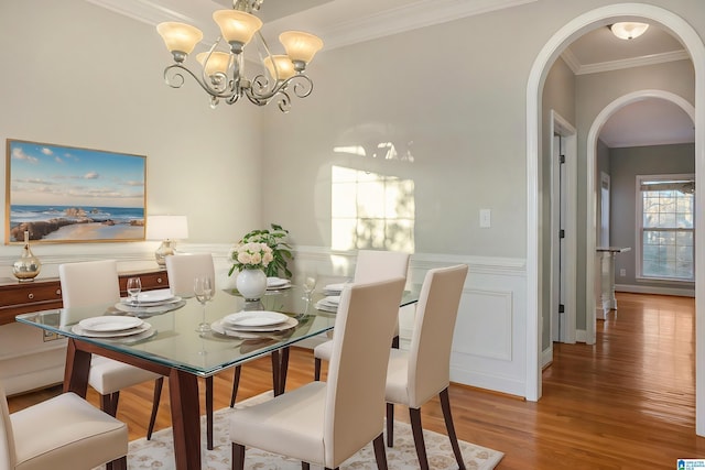 dining space featuring wood-type flooring, ornamental molding, and a chandelier