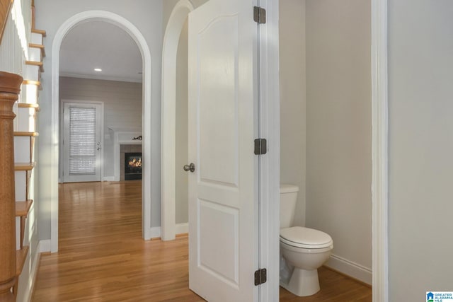 bathroom featuring toilet, hardwood / wood-style floors, and a tile fireplace