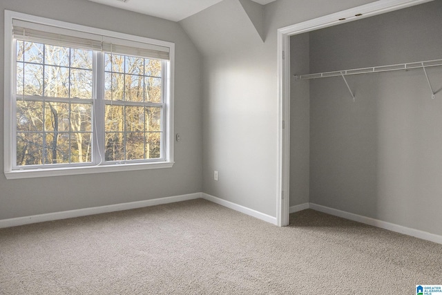 unfurnished bedroom featuring carpet flooring, vaulted ceiling, and a closet