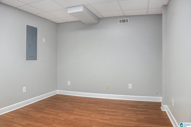 empty room with hardwood / wood-style flooring, a paneled ceiling, and electric panel