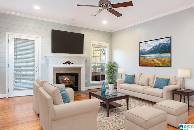 living room featuring ceiling fan, ornamental molding, and light wood-type flooring