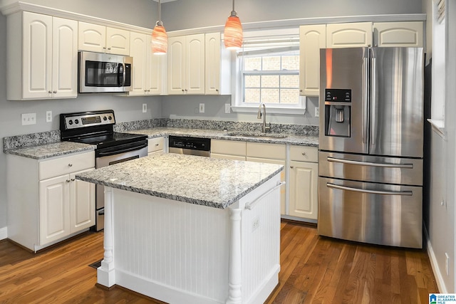 kitchen with pendant lighting, sink, a center island, stainless steel appliances, and light stone countertops