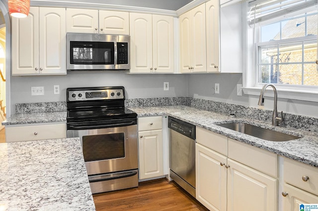 kitchen featuring sink, light stone counters, white cabinetry, appliances with stainless steel finishes, and dark hardwood / wood-style floors