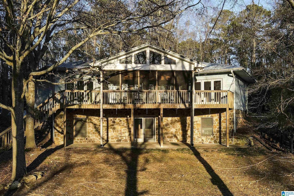 rear view of house featuring a wooden deck, a patio area, and a sunroom