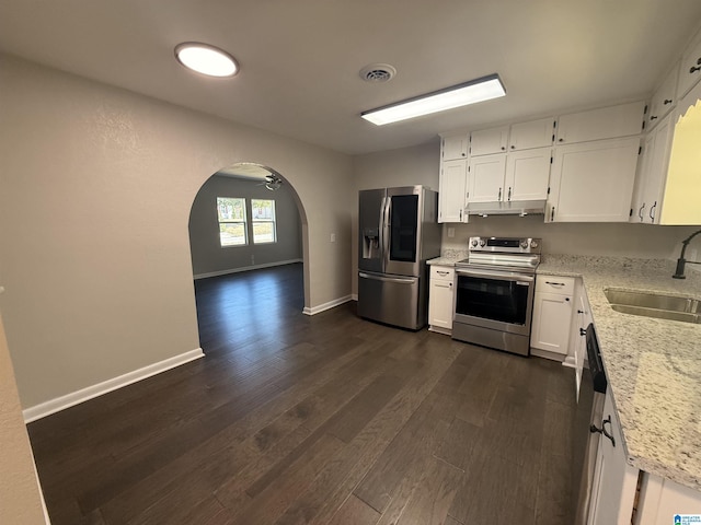 kitchen featuring sink, white cabinets, stainless steel appliances, light stone countertops, and dark wood-type flooring