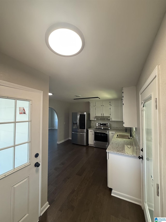 kitchen with sink, appliances with stainless steel finishes, light stone countertops, white cabinets, and dark hardwood / wood-style flooring