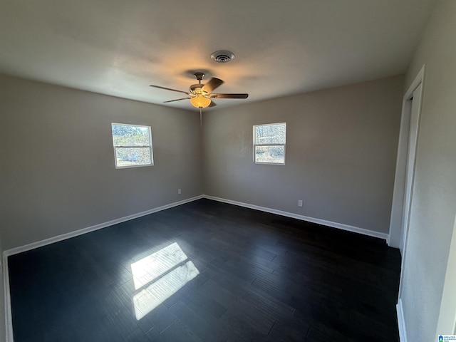 spare room with dark wood-type flooring, a wealth of natural light, and ceiling fan