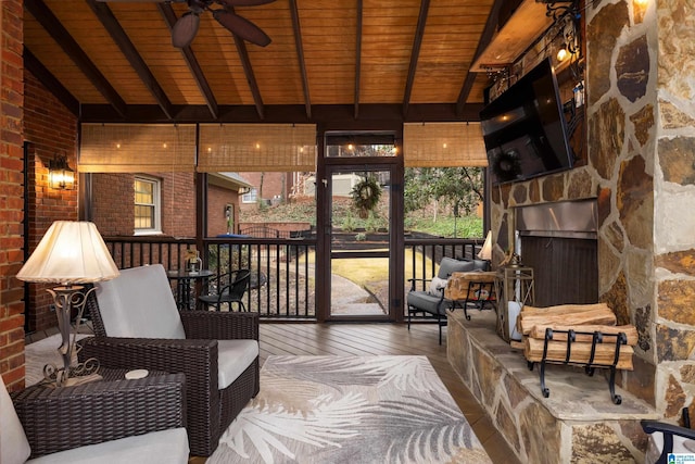 sunroom / solarium with lofted ceiling with beams, wood ceiling, and ceiling fan