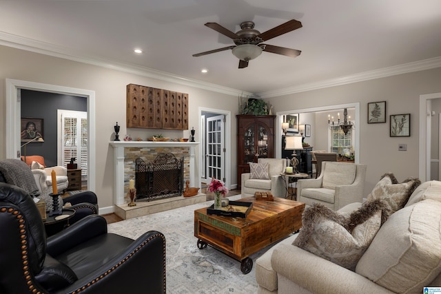 living room with ornamental molding, ceiling fan with notable chandelier, and a fireplace