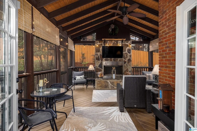 sunroom / solarium featuring wood ceiling, ceiling fan, an outdoor stone fireplace, and vaulted ceiling with beams