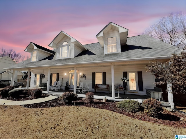 cape cod home featuring covered porch