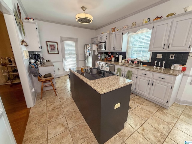 kitchen featuring sink, a center island, ornamental molding, stainless steel appliances, and white cabinets