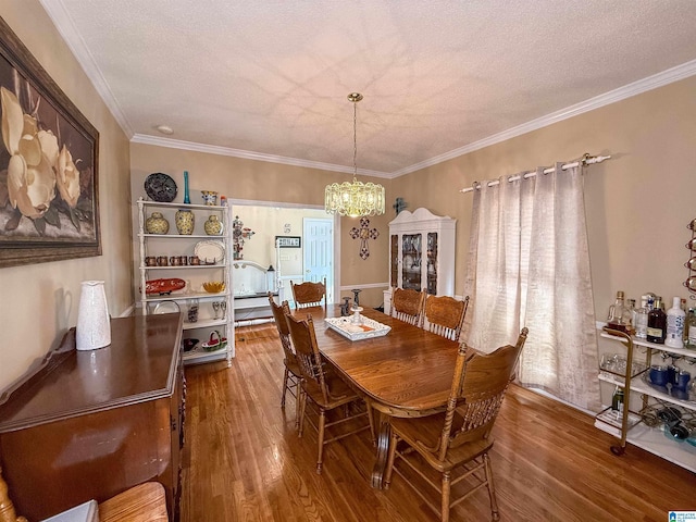 dining room with crown molding, hardwood / wood-style floors, a notable chandelier, and a textured ceiling