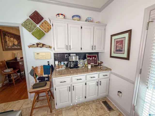 kitchen with white cabinetry, ornamental molding, stone countertops, and decorative backsplash