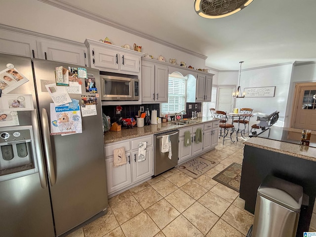 kitchen with pendant lighting, white cabinetry, stainless steel appliances, tasteful backsplash, and ornamental molding