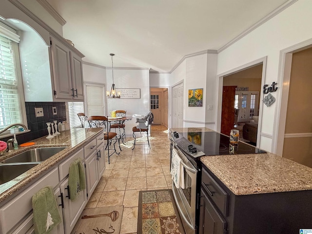 kitchen featuring crown molding, plenty of natural light, a notable chandelier, electric stove, and decorative backsplash